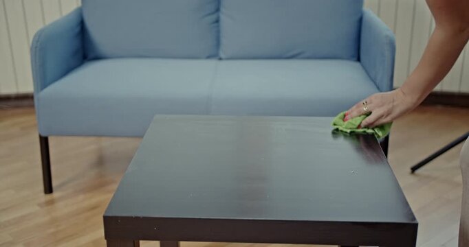 A woman meticulously cleans a dusty table, first wiping it with a cloth, then spraying it and cleaning it again. This video features satisfying cleaning sounds.