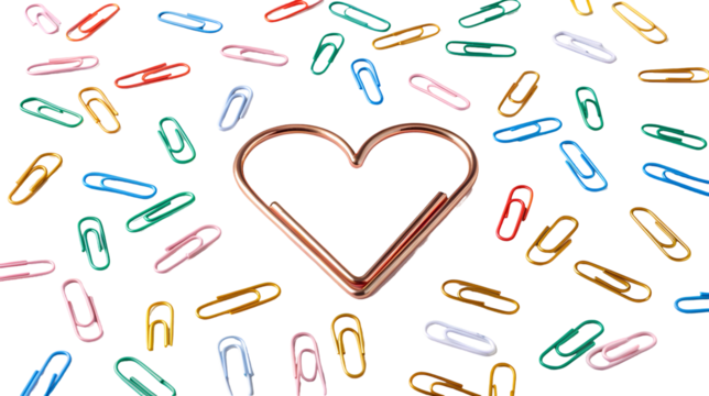 Rose gold heart-shaped paper clip surrounded by scattered multicolored office supplies isolated on transparent background