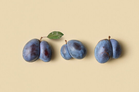 Three plums with unusual shape on beige background