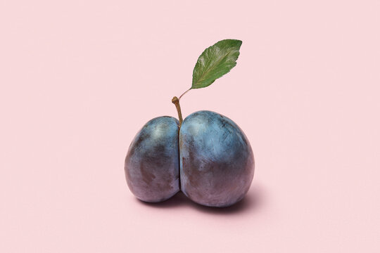 Split plum with leaf on pastel background