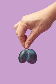 Hand holding split plum on purple background