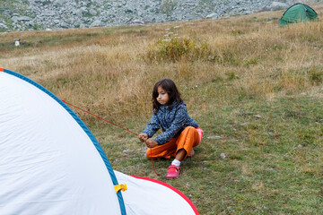 Child Setting up a Tent in a Grassy Camping Area