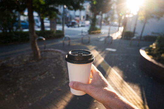 Hand holding a coffee cup in the city