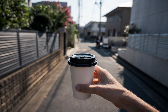 Hand holding a coffee cup in the city