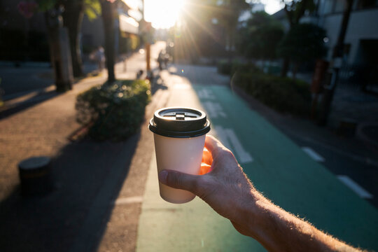 Hand holding a coffee cup in the city