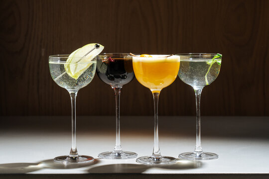 Four colorful cocktails in coupe glasses