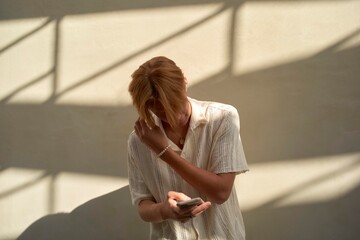 Man Interacting With Smartphone Under Soft Sunlight Shadows