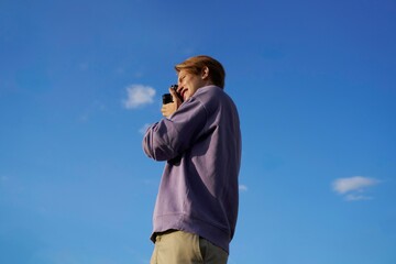 Young Man Taking Photos Against a Clear Blue Sky