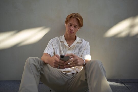 Young Man Enjoying Leisure Moments While Texting on His Phone