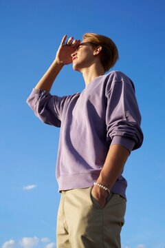 Young Man Gazing Towards the Horizon Under a Bright Blue Sky
