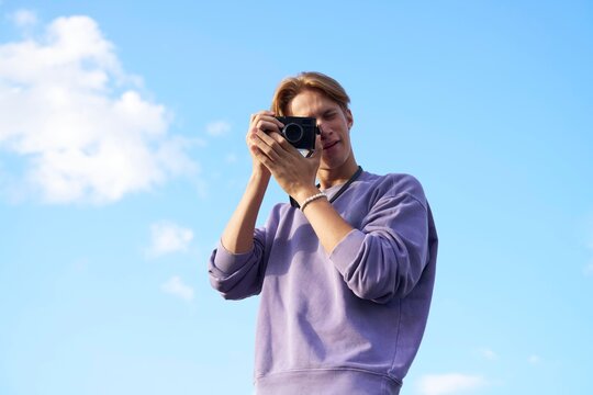 Young Man Captures Memories With Camera Against Clear Blue Sky