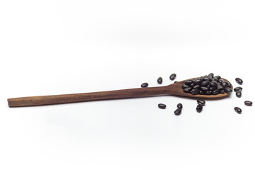 Wooden spoon with dry black beans isolated