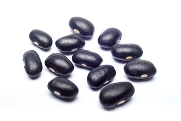 Black beans scattered on white background in close-up shot