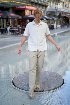 Young Man Walking on Water Feature in Urban Square During Daytime