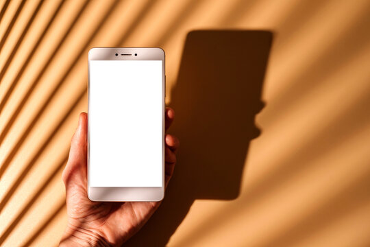 Woman's hand holding smartphone with white empty screen.