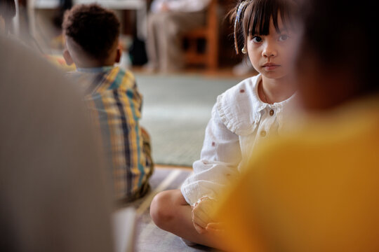 Young girl sits cross-legged in a group setting.