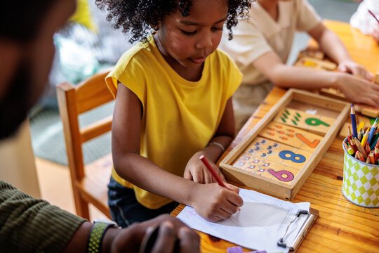 Child learning numbers and drawing with adult supervision.