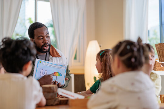 Teacher instructs children using a letter "U" worksheet.