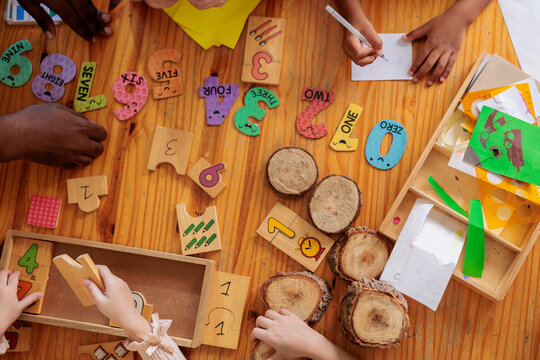 Children learn math with wooden numbers and art supplies.