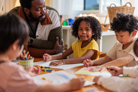 Teacher and children drawing together at a table.