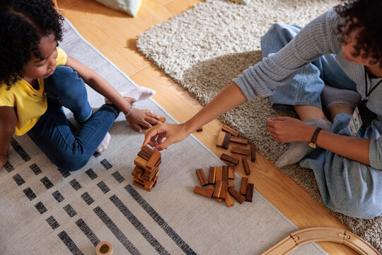 Child and adult play wooden block stacking game together.