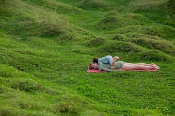Caucasian woman doing yoga with her little son outdoors. 