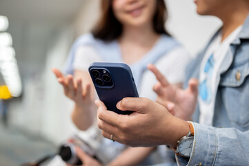 Close up of asian tourist couple go on trip man woman talking looking at phone as waiting in airport