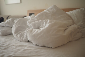 Messy bed with rumpled white sheets in quiet room