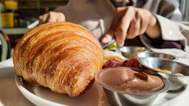Fresh croissant with chocolate and salad at a cafe table
