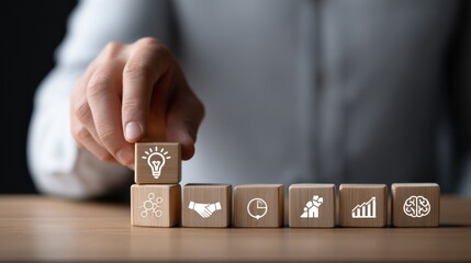 Hand Arranging Wooden Blocks with Idea, Partnership, Statistics, Growth, Brain Icon on Table