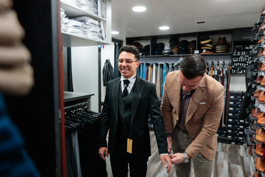 Tailor adjusting a man&rsquo;s suit sleeve during fitting