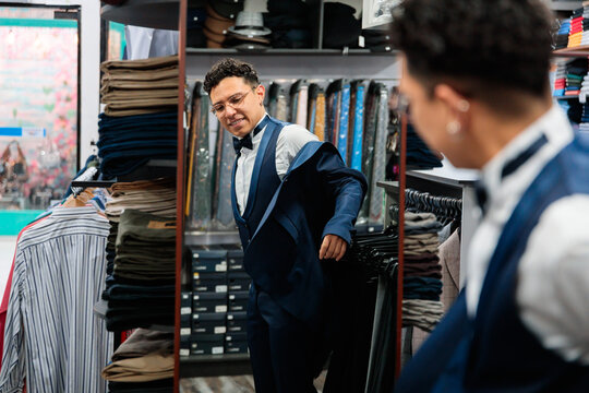 Man trying on blue suit jacket in front of mirror
