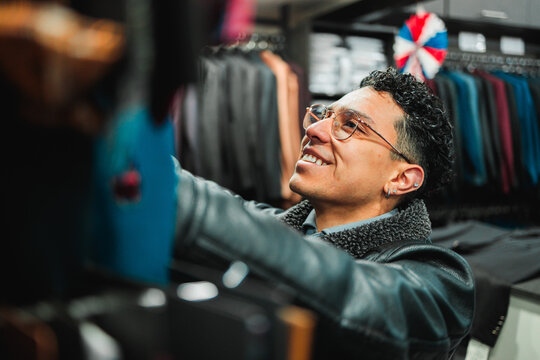 Smiling latin man choosing clothes in boutique