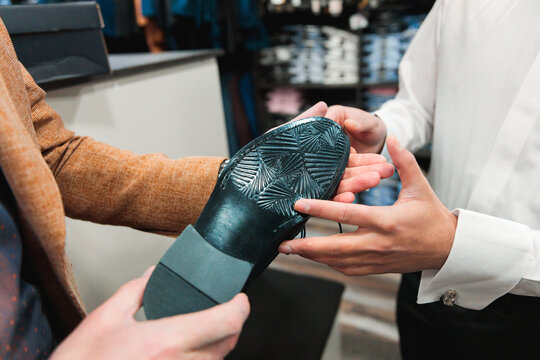 Customer examining sole of formal shoe with vendor