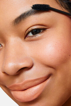 Extreme close-up of Latina woman brushing eyebrow with spoolie