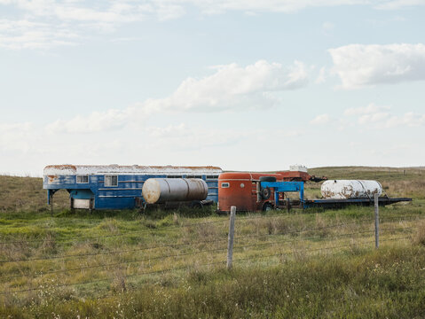 Rusty trailers and tanks on prairie field