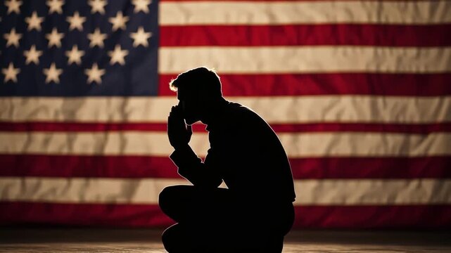 Silhouette of a soldier praying in front of the American flag. Patriotism concept.