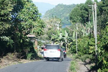 Cars pass on the road surrounded by beautiful hill views.