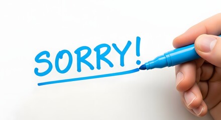 Hand writing sorry with a blue marker on a white surface