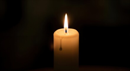 Close-up of a single white candle burning brightly in the dark with melted wax dripping down its side, creating a warm and peaceful atmosphere.