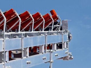 Mechanical system with vibrant red components showcased against a clear blue sky in a modern industrial setting