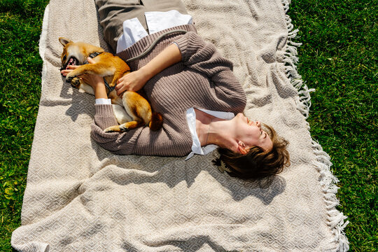 Woman lying on blanket playing with dog 