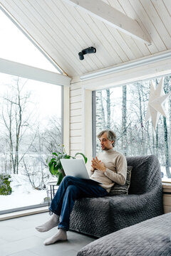 Man working on laptop remotely with winter forest view during holiday