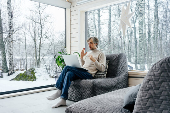Man working on laptop at home with winter forest view