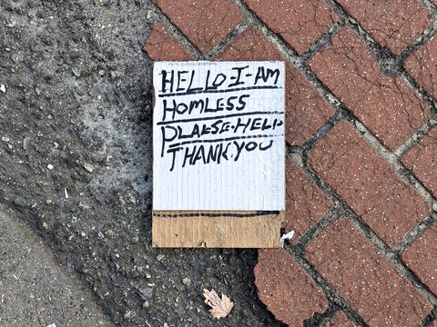 Cardboard homeless sign on street pavement