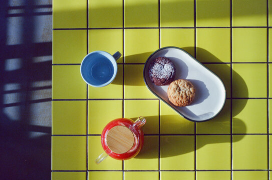 Freshly baked cookies and tea served on a bright yellow table 