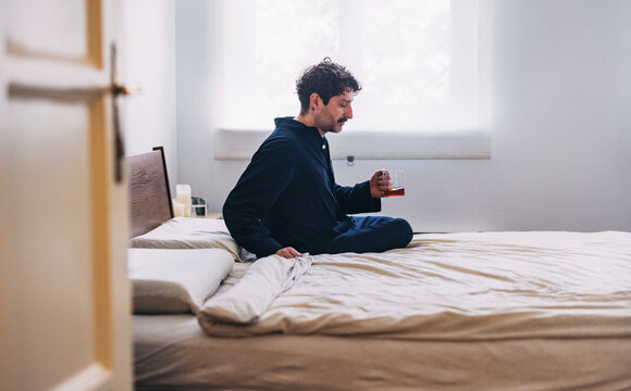 Man Relaxing in Bed While Enjoying Morning Coffee in a Cozy Bedroom