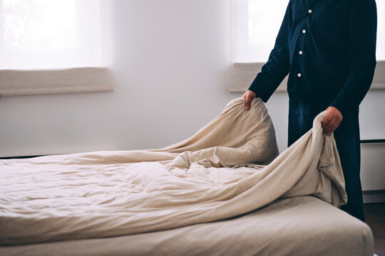 Person Straightening Beige Linens on a Comfortable Bed