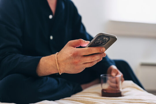 Man Relaxing and Using Smartphone While Holding a Glass at Home