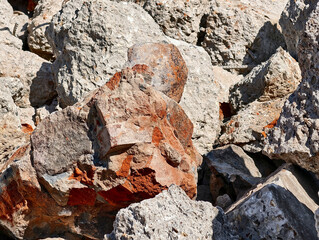 Natural rock formation displaying various textures and colors under bright sunlight at a construction site